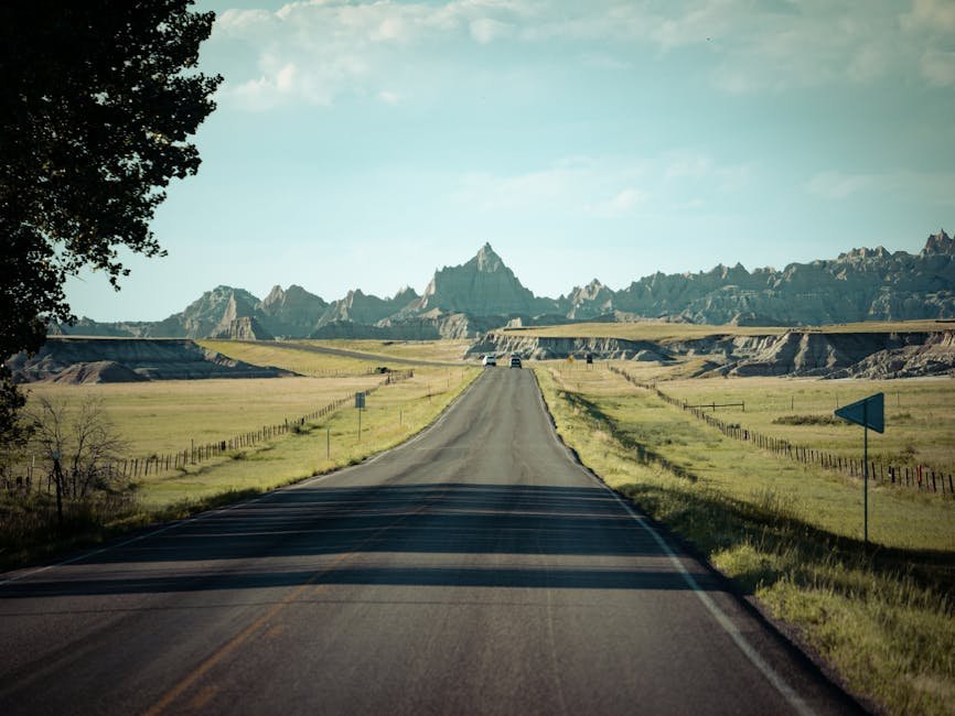 A scenic road stretching through the Badlands landscape under a clear sky.